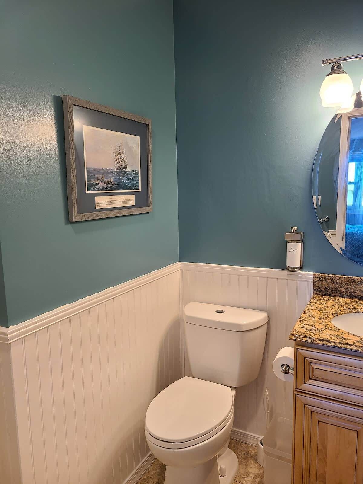 A bathroom with a toilet, vanity, and a framed picture on the wall.