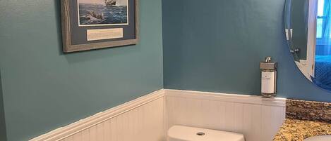 A bathroom with a toilet, vanity, and a framed picture on the wall.