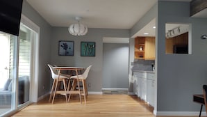 Eine moderne Küche mit Holzausstattung, einem Essbereich mit Tisch und Stühlen sowie einer Deckenleuchte.