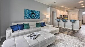 A modern living room with a sectional sofa, a coffee table, and a kitchen in the background.