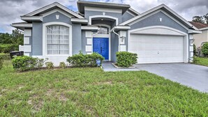 A modern two-story house with a blue front door, white garage door, and a well-maintained lawn.