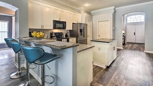 A modern kitchen with white cabinets, stainless steel appliances, and a central island with bar stools.