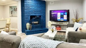 Un salon moderne avec un mur d’accent bleu, une cheminée, un téléviseur à écran plat et des sièges confortables.