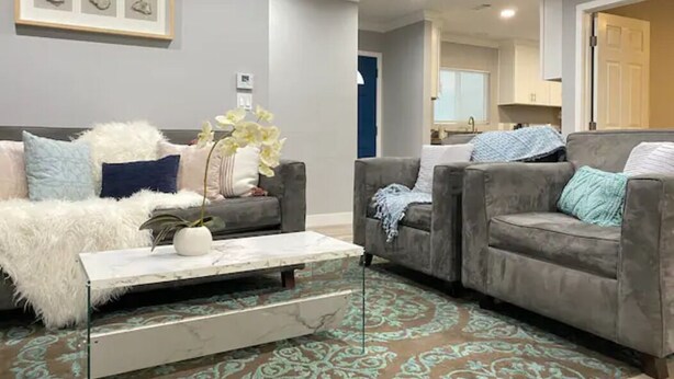 Un salon avec deux canapés gris, une table basse blanche et un tapis à motifs.