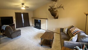A living room with a fireplace, a mounted deer head, a ceiling fan, and a couch with decorative pillows. - On the Rio Grande. Direct ATV Access from the property to National Forest Roads. (South Fork)