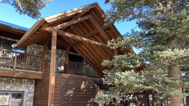A log cabin with a stone foundation, wooden balcony, and a stone bench. - On the Rio Grande. Direct ATV Access from the property to National Forest Roads. (South Fork)