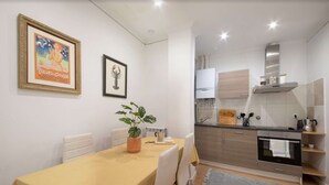 A compact kitchen with modern appliances, a dining area with a table and chairs, and a framed picture on the wall. - Spacious, family-friendly apartment right on Zurriola Beach (Donostia)
