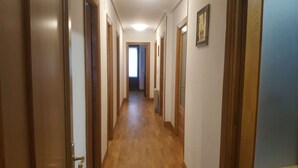 Un long couloir étroit, avec des portes en bois et un radiateur au mur.