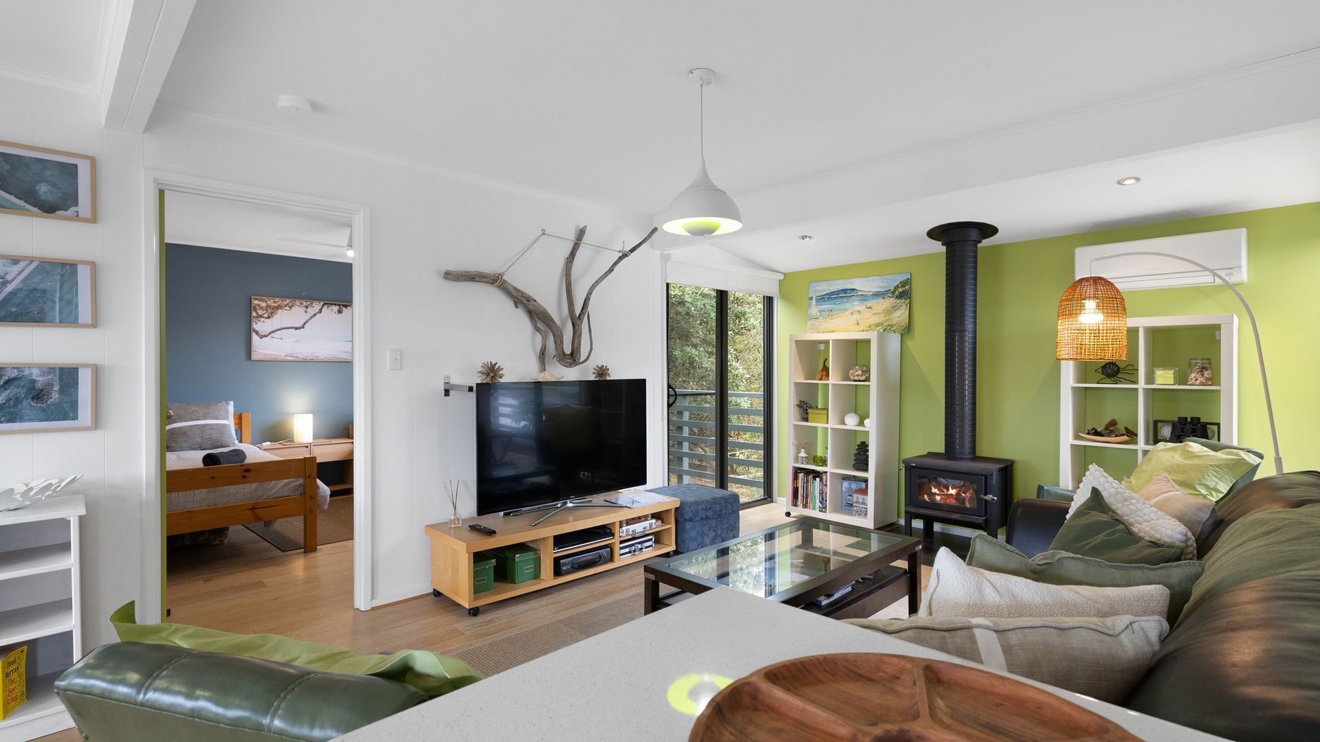Een moderne woonkamer met een flatscreen televisie, een glazen salontafel, een bank, een houten kast en een boekenkast.