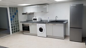 Una cocina moderna con electrodomésticos de acero inoxidable, horno integrado, lavadora y refrigerador.