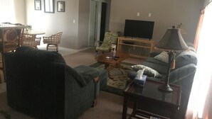 Uma sala de estar com sofá, mesa de centro, televisão e abajur.