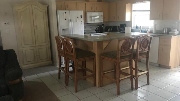 Cozinha com ilha central, cadeiras de madeira e um armário.