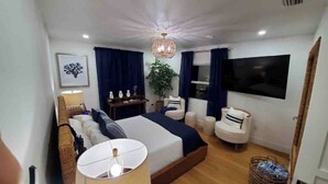 A modern bedroom with a large bed, a TV, a ceiling light, and a plant. - Luxurious Oceanfront Ormond Getaway (Ormond Beach)