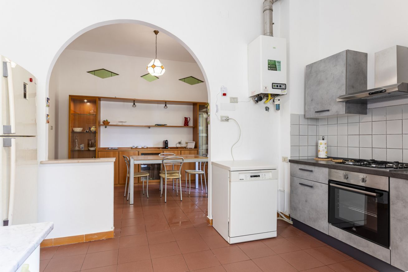 Una cuina compacta amb rentaplats, forn i zona de menjador amb cadiretes i taula.
