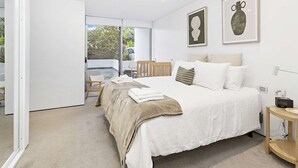 A bedroom with a large bed, a wooden chair, and a small table.