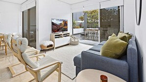A modern living room with a sofa, chairs, a TV, and a sliding glass door leading to an outdoor area.