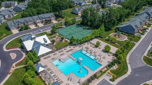 Vista aérea de una zona residencial con una piscina grande, canchas de tenis y un club social.