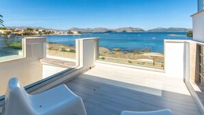 A modern balcony with a clear view of the sea and distant mountains.
