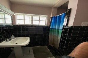 Een bad/douchecombinatie, een haardroger, handdoeken, zeep