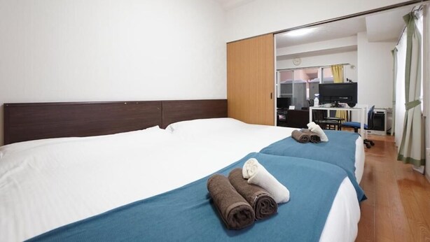 A hotel room with a large bed, a desk, a chair, a television, and a mirror. - IKminami6jo residence 101 (Sapporo)