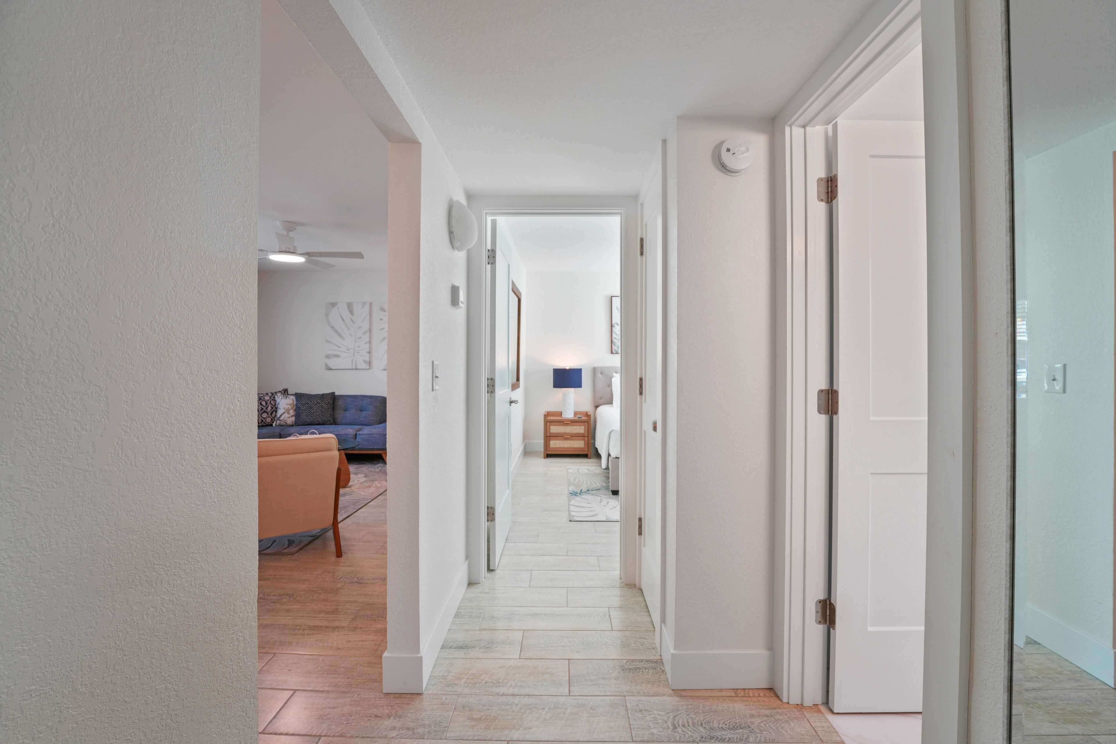 A hallway with a sofa and a lamp in the background.