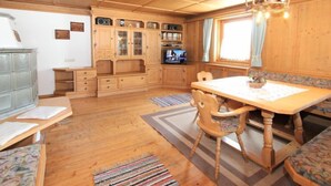 A cozy wooden cabin interior with a dining table, chairs, a television, and built-in cabinets.
