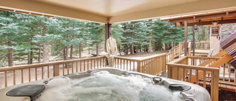 Ein Whirlpool auf einer Holzterrasse mit Blick auf einen Wald.