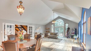 A spacious living area with a dining table, chairs, a chandelier, and a large window. - Riverfront Retreat in Nathrop: Fire Pits & Hot Tub (Nathrop)