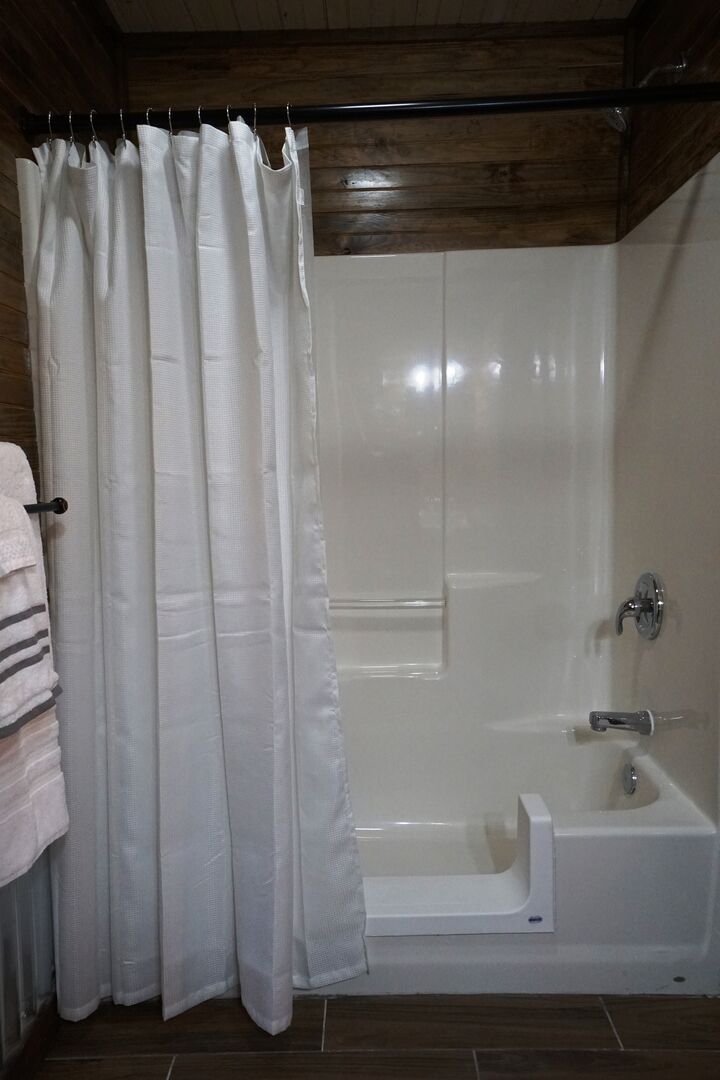 A bathroom with a shower curtain, a bathtub, and a towel rack.