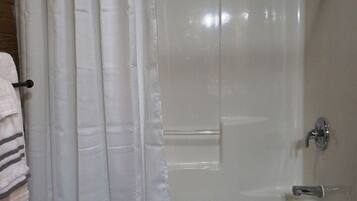 A bathroom with a shower curtain, a bathtub, and a towel rack.