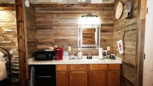 A compact kitchen with wooden cabinetry, a microwave, a coffee maker, and a sink. - Bakery Haus- Tres Leches | Pleasant Cabin for 2 (Fredericksburg)