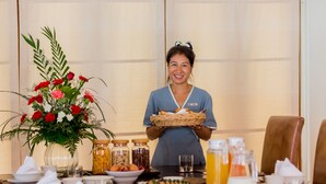 A hotel dining area with a table set for breakfast, including a variety of dishes, a fruit platter, and a floral centerpiece. - Baan Chao Lay (Koh Samui)