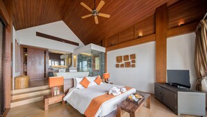 Une chambre spacieuse avec un grand lit, un plafond en bois et un téléviseur posé sur une table de chevet.