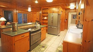 Eine Holzhüttenküche mit Herd, Backofen, Kühlschrank und Spüle.