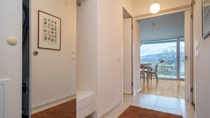 A hallway with a framed picture, a white bench, and a brown rug. - Apartment ‘Pfirsichblüte’ on idyllic Family Farm House with Balcony & Mountain View (Lindau)