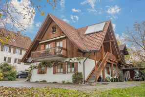 A two-story wooden house with a balcony, a staircase, and a garage.