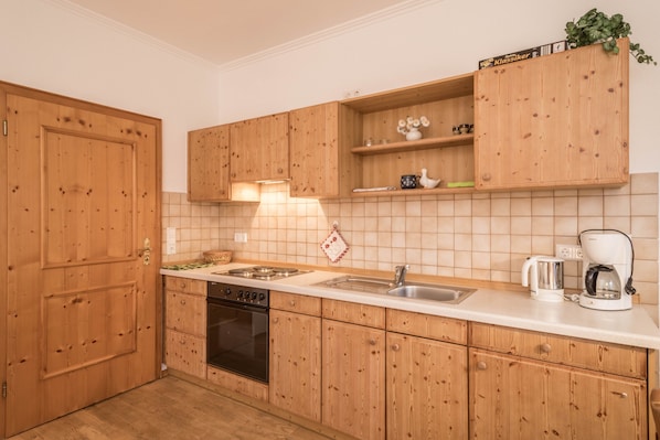A kitchen with wooden cabinets, a stove, a sink, and a coffee maker.
