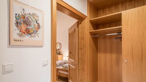 Un armario de madera con barra para colgar, una cama con colcha floral y un cuadro en la pared.