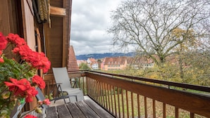 Un balcón de madera con vistas a casas y montañas.