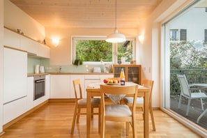 Una cocina moderna con armarios de madera, una mesa de comedor con sillas y un amplio ventanal con vistas a zonas verdes.