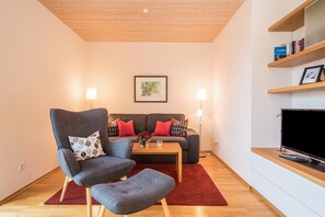 A modern living room with a sofa, two armchairs, a coffee table, a TV, and a bookshelf. - Comfy Apartment ‘Rosenblüte’ on idyllic Family Farm House (Lindau)