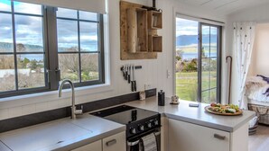 Une cuisine moderne dotée de grandes fenêtres, d’une cuisinière intégrée et d’un porte-ustensiles en bois.