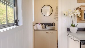 Une cuisine étroite avec des meubles blancs, un plan de travail en bois et une fenêtre donnant sur un espace verdoyant.