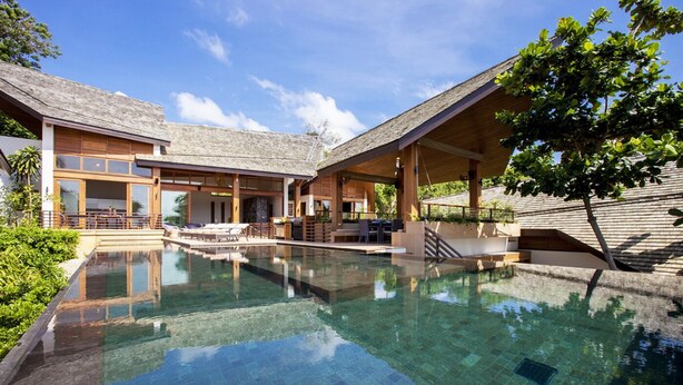 Un hotel moderno con una gran piscina al aire libre, zonas de estar cubiertas y un amplio patio.