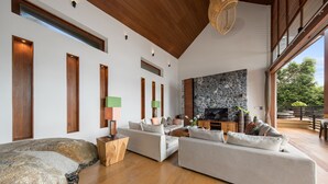 Amplia sala de estar con chimenea de piedra, vigas de madera en el techo y una gran formación rocosa.