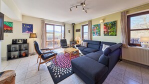 A living room with a sofa, chairs, a coffee table, a fireplace, and artwork on the walls. - Green Valley Park Stárkov 6 by Interhome (Stárkov)