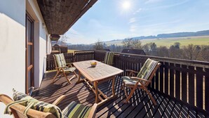A wooden deck with a table and chairs, a view of the countryside, and a clear sky. - Green Valley Park Stárkov 6 by Interhome (Stárkov)