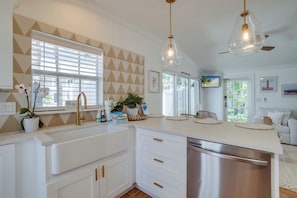 A modern kitchen with white cabinetry, stainless steel appliances, and pendant lighting.