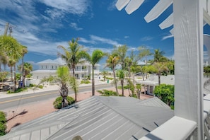 A coastal view with a white building, palm trees, and a clear sky.
