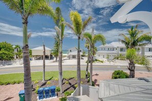 A beachfront property with palm trees, a road, and white buildings.